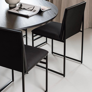 Isabell Dining Chairs in black velvet by Crea paired with a round black oak dining table in a minimalist neutral-toned interior.