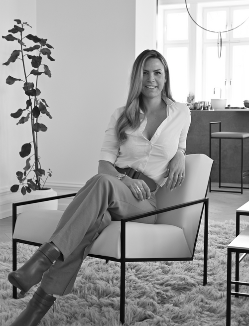 Alexandra Pettersson, founder and designer of by Crea, seated in a Scandinavian accent chair within a minimalistic interior. Captured in a relaxed pose, reflecting the brand’s ethos of elegant simplicity and timeless design.