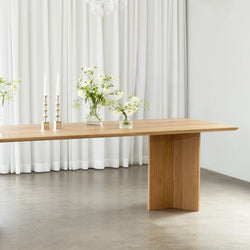 Ann dining table made of oak, showcasing natural warmth with clean lines, complemented by floral decor and candles.
