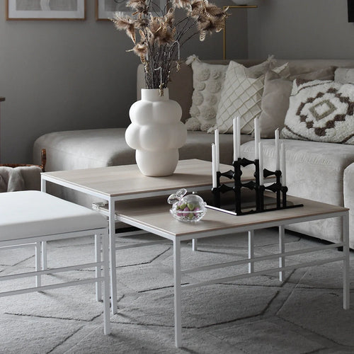 Anton nesting table set with white frame and oak tops, styled in a modern neutral-toned living room.