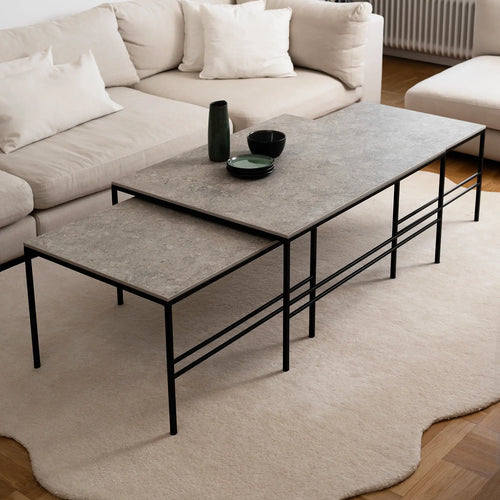 Scandinavian Anton Coffee Table set in Grigio Dekton with black steel frame by by Crea. Three nesting tables arranged in a modern beige living room, highlighting minimalist handmade furniture with durable Dekton surfaces.
