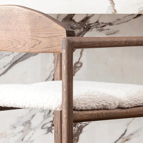 Dark oak bar stool with ivory bouclé seat against a marble background, showcasing luxury and timeless design.