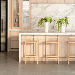 Ebba Bar stools in oak at a modern kitchen island with marble countertop and decorative plants.