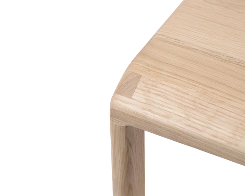 Close-up of the Eva Bar Stool by Crea highlighting the rounded seat corner crafted in solid light oak, showcasing the natural wood grain and Scandinavian minimalist design.