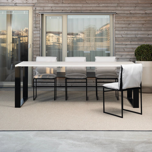 Isa outdoor chairs with black frames and white cushions paired with the Diana outdoor dining table by by Crea, styled on a modern balcony with wood paneling and city views.