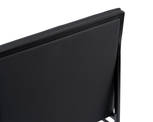 Angled close-up of the Isabell Dining Chair from by Crea, highlighting the smooth black vegan leather backrest framed by a minimalist black steel structure, showcasing Scandinavian craftsmanship.