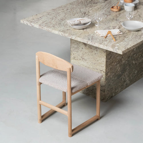 Karin dining chair in oak with greige bouclé, showcasing soft, neutral style and solid wood craftsmanship at modern dining table.
