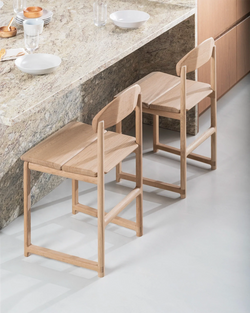 Karin dining chairs by by Crea in solid oak, placed at a stone kitchen island, showcasing minimalist Scandinavian craftsmanship and a warm natural finish.