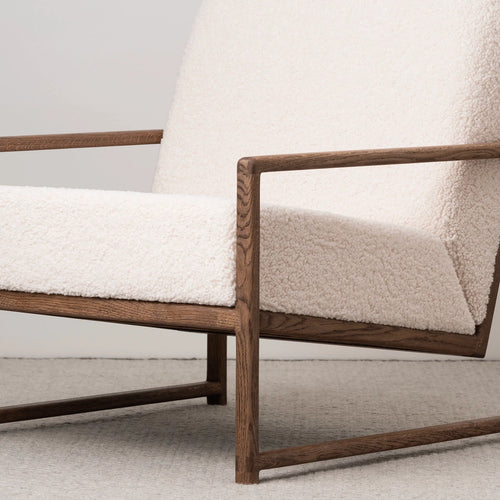 Dark oak armchair with soft ivory bouclé upholstery, adding warmth and Scandinavian comfort to any cozy space.