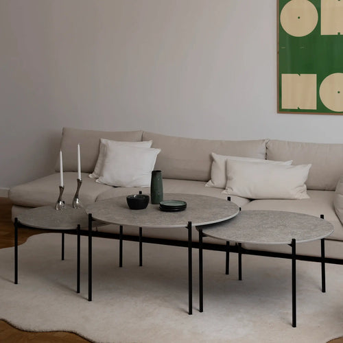 Leo Coffee Table 3-set by by Crea in Grigio Dekton with black steel frame, styled with green ceramics and silver candle holders in a Scandinavian living room with modern wall art and a beige sectional. Handmade designer furniture for contemporary interiors.