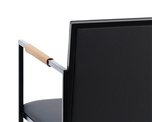 Detail of the Sella Dining Chair backrest in vegan leather with black powder-coated steel frame and tan leather-wrapped armrest, Scandinavian minimalist design.