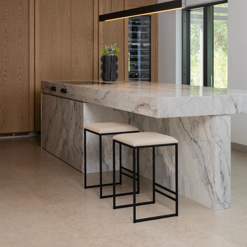 Svea black bar stools with sand leather seats at a modern kitchen island with marble countertop.