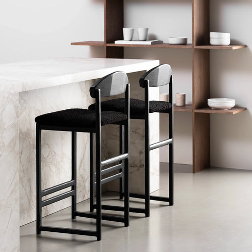 Sleek black oak bar stools with black bouclé seats at a modern kitchen counter.