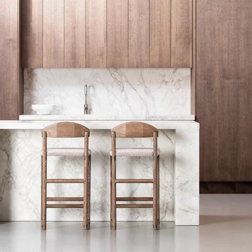 Ted bar stools in dark oak with greige bouclé seats, enhancing a modern kitchen with marble countertops.