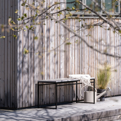 Wilma outdoor bench in black with sleek Keon dekton top, featuring a modern design in a serene garden setting.