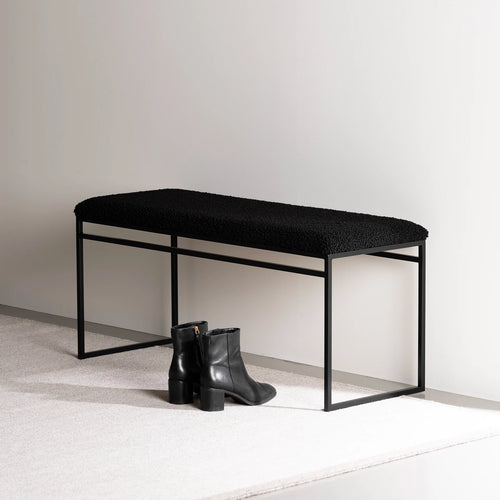 Wilma bench in black bouclé with clean lines, ideal for a minimalist décor, paired with stylish black boots.