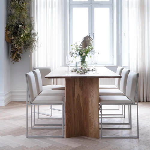 Ann dining table in oak with modern white chairs, showcasing elegance and natural warmth in a stylish dining space.