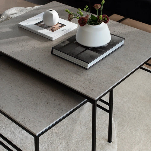Close-up front view of the Anton Nesting Coffee Table from by Crea, featuring a minimalist black steel frame and durable Dekton top, styled with modern decor in a neutral interior.
