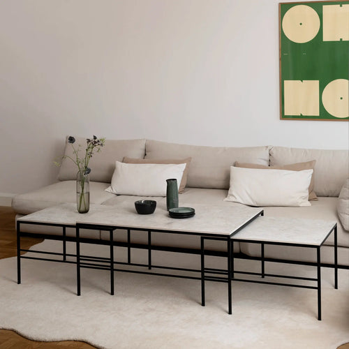 Anton Coffee Table Large Set with black steel frame and Sabbia Dekton top by by Crea, Scandinavian minimalist design. Shown in a modern living room with a light beige sectional sofa, soft cream rug, green abstract wall art, and decorative ceramic vases on the table. Perfect for stylish Scandinavian interiors, handmade in Sweden.