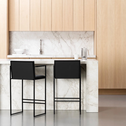 Bruno bar stools with jade black leather and black frame in modern kitchen setting with marble countertop.