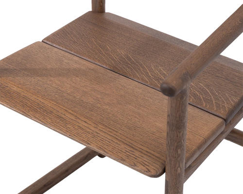 Detail of Erik Dining Chair seat in solid dark oak, showcasing seamless joinery and natural wood grain | by Crea.