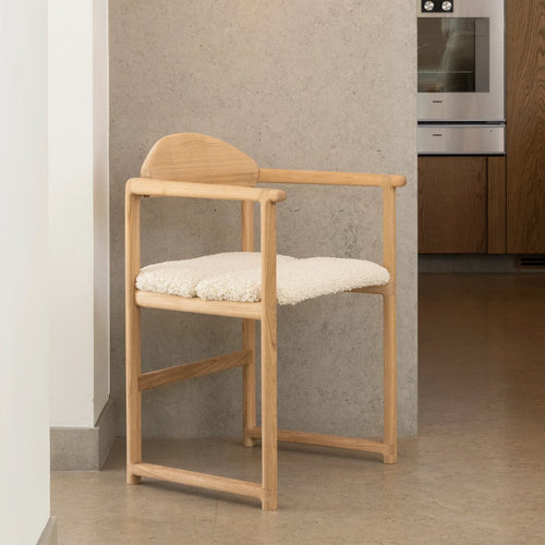 Erik dining chair in oak with ivory bouclé, showcasing warm wood and soft texture for relaxed dining.