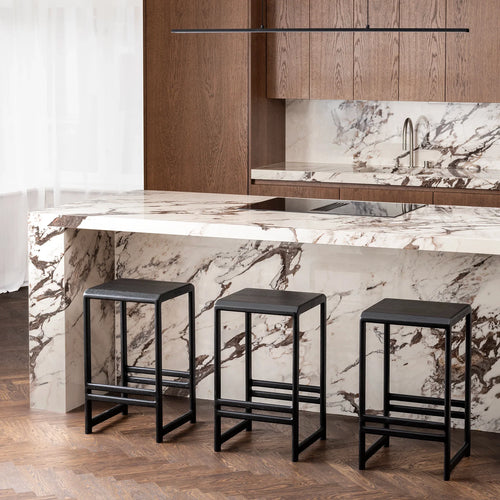 Eva Bar stools in black oak at a modern kitchen island with marble countertop, showcasing clean lines and a slim profile.