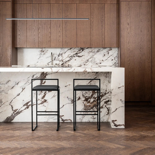Freja bar stools in black leather against a marble kitchen island backdrop, showcasing minimalistic design and style.