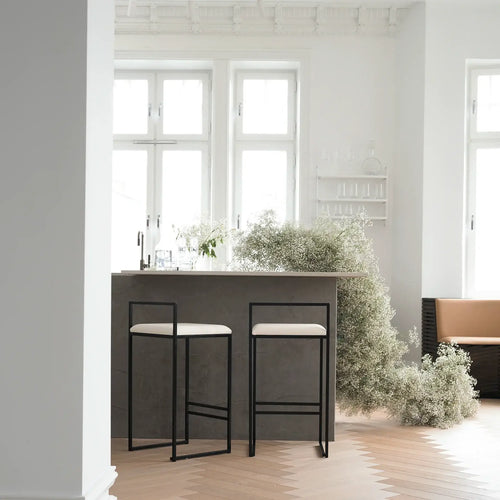 Freja bar stools with ivory leather cushions and black steel frame in a modern kitchen setting.