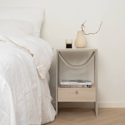 Iris bed table in beige with lunar dekton top next to a bed, stylish and durable bedroom furniture upgrade.