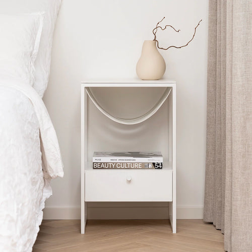 Iris bed table in white with minimalist design, featuring a drawer and decorative vase, ideal for modern interiors.