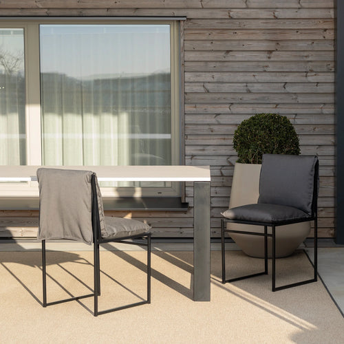 Isa outdoor chair in black onyx acrylic, elegantly placed beside a modern dining table on a stylish patio.