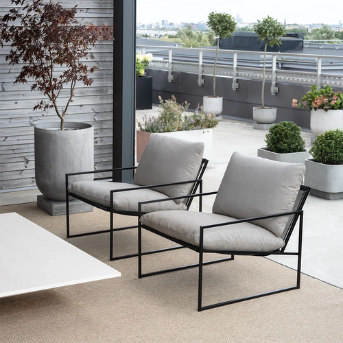 Modern outdoor seating with two grey cushioned lounge chairs and a stylish planter on a rooftop terrace.