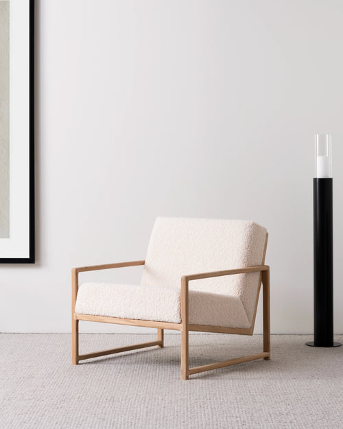Kent wood accent chair in natural oak with ivory bouclé upholstery, styled in a minimalist modern interior by Crea.