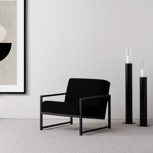Minimalist black oak armchair with black bouclé seat, offering modern design and relaxed support in stylish interior.