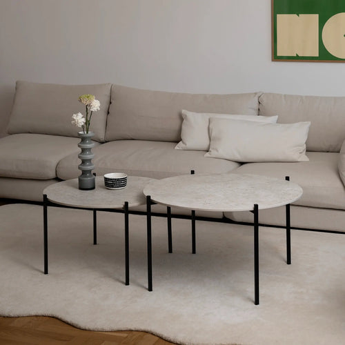 Leo Coffee Table 2-set by by Crea with Sabbia Dekton tops and black steel frames, styled with sculptural vase and ceramics in a Scandinavian living room with a beige sectional and soft ivory rug. Handmade designer coffee tables for modern homes.