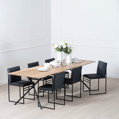 Melker Dining table in black with natural oak top, surrounded by sleek black chairs, showcasing modern elegance.