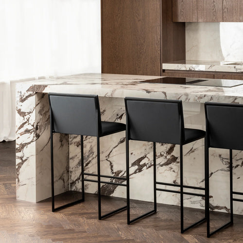 Philip bar stool in black leather featuring a sleek design, paired with a marble kitchen island for modern elegance.