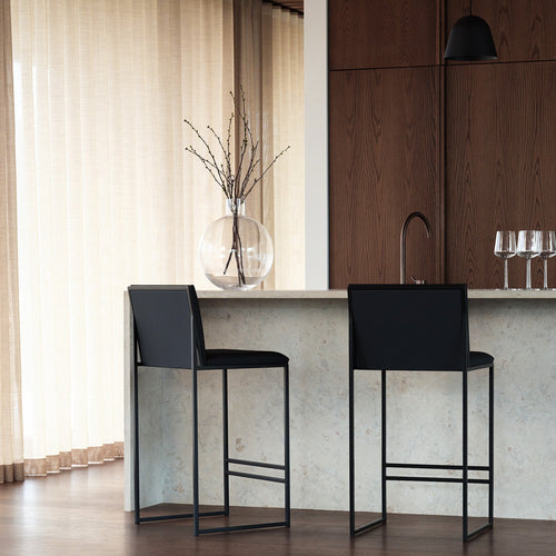Modern Philip bar stools with black leather seats and black frames, set at a contemporary kitchen island.