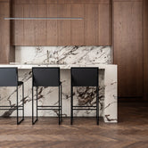 Minimalist black bar stools with backrests in a luxury marble and dark oak kitchen – Scandinavian modern seating by Crea.