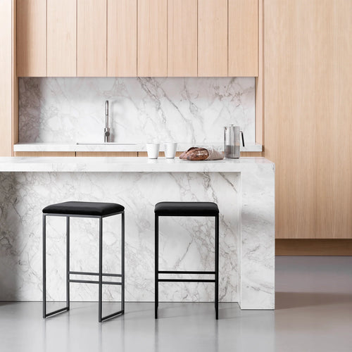 Svea bar stool in black velvet with a sleek black frame, set against a modern marble kitchen countertop.