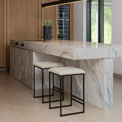 Svea bar stools with ivory bouclé seats and black frames by a modern marble kitchen island.