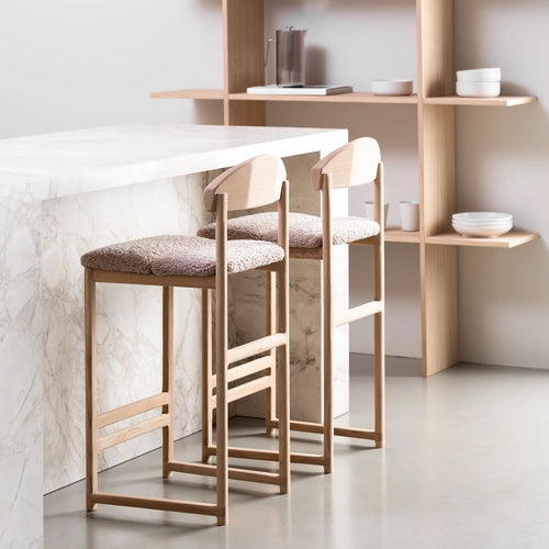 Ted bar stools in oak with greige bouclé seats, complementing a modern kitchen countertop.