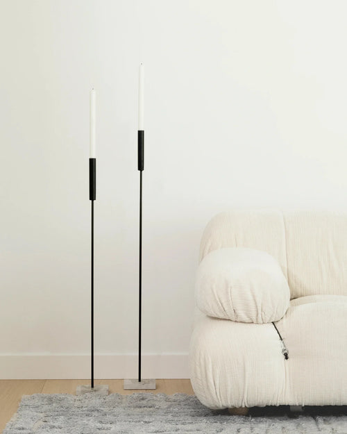Two by Crea Vera Candle Holders in black with Moorland Caesarstone bases styled next to a white Camaleonda Sectional Sofa by B&B Italia in a minimal living room setting.