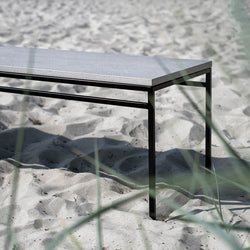 Wilma outdoor bench in black with sleek Keon dekton top, set against sandy background, perfect for gardens.
