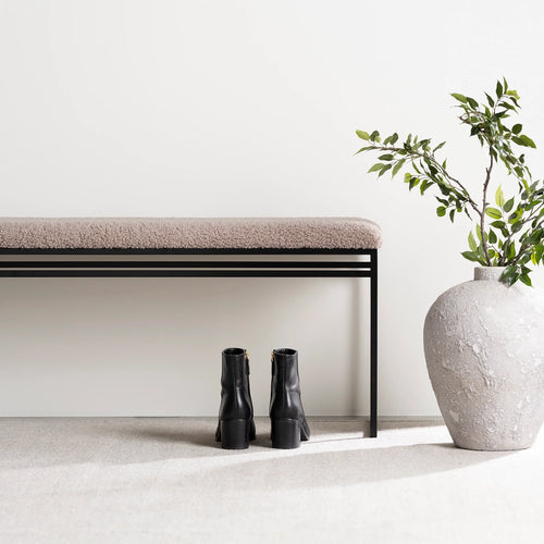 Wilma bench in black with greige bouclé, styled with black boots and a decorative vase for modern interiors.