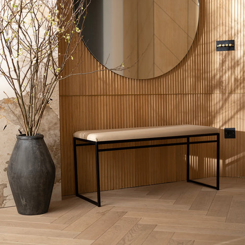 Wilma bench in black with latte vegan leather, set against a stylish wooden wall and modern decor.