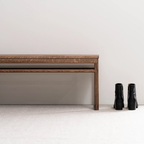 Wilma wood bench in dark oak finish next to stylish black boots, adding warmth to any space.
