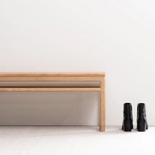 Wilma wood bench in solid oak beside stylish black boots, perfect for creating a Scandinavian style entryway.