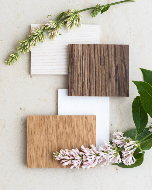 Three wood samples in various finishes with flowers and green leaves, showcasing quality and texture options.